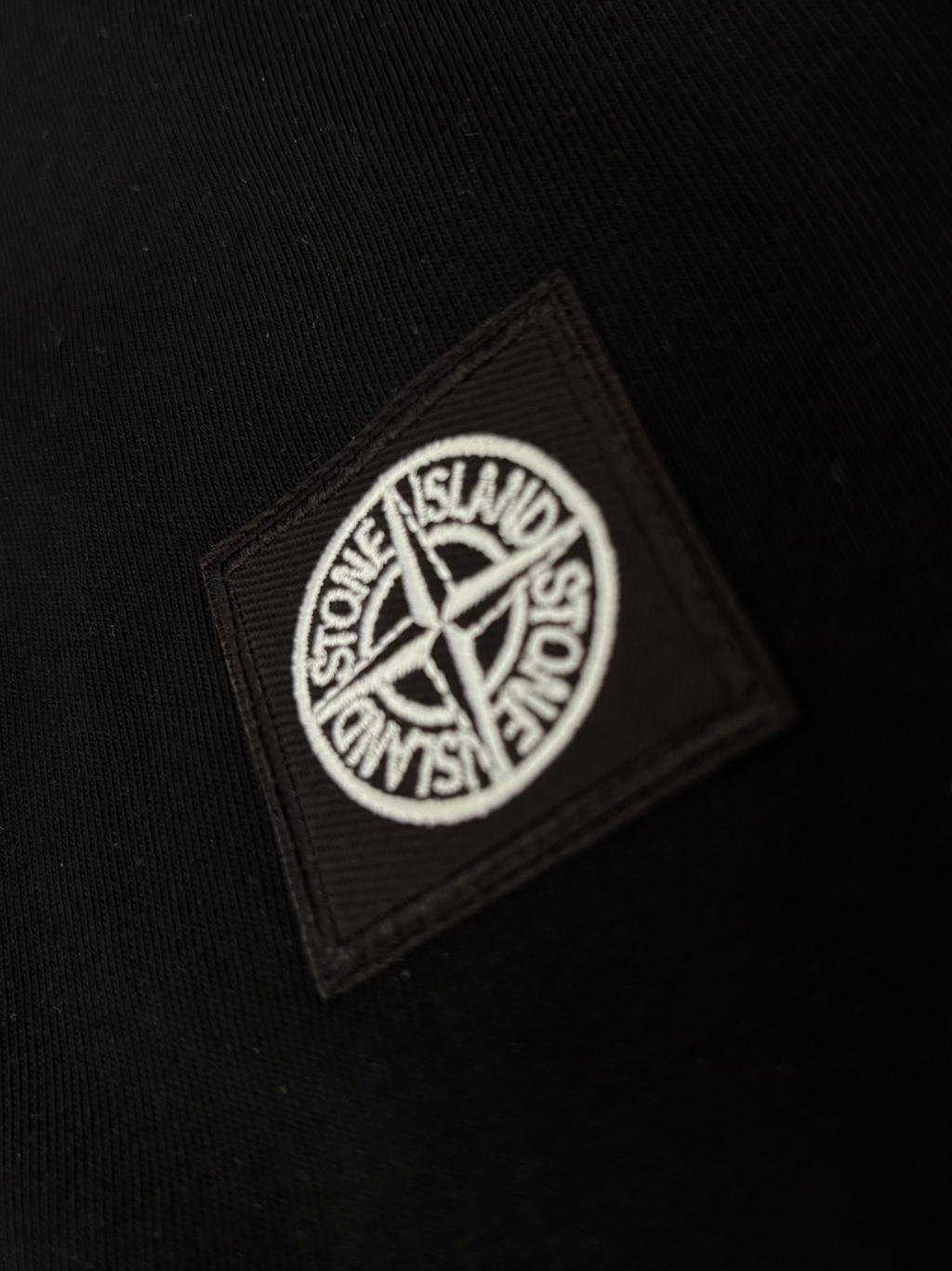 Black fabric with a Stone Island logo patch