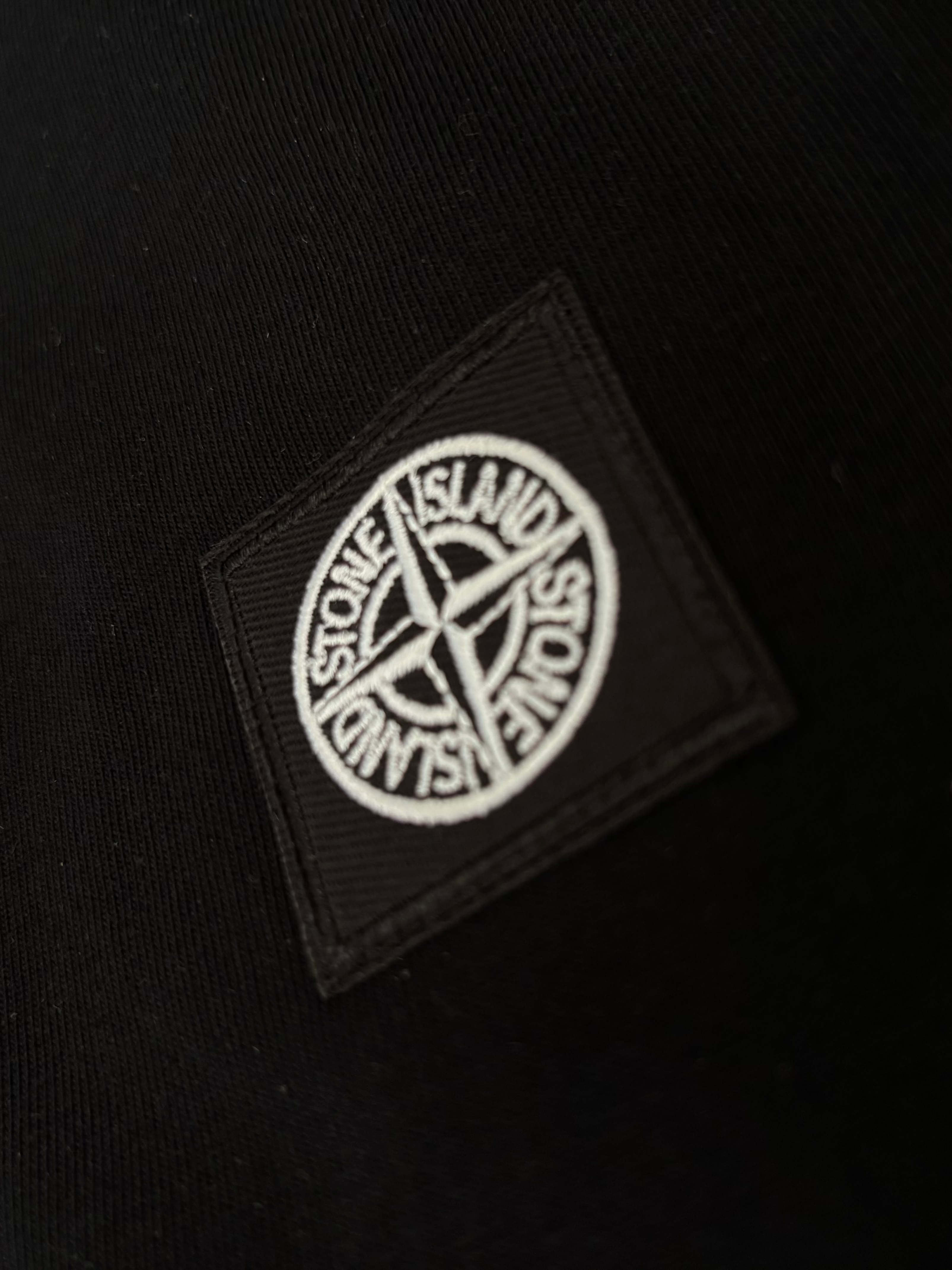 Black fabric with a Stone Island logo patch